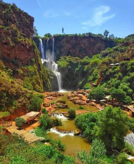 A waterfall cascading into a river surrounded by lush greenery and rocky cliffs. 1