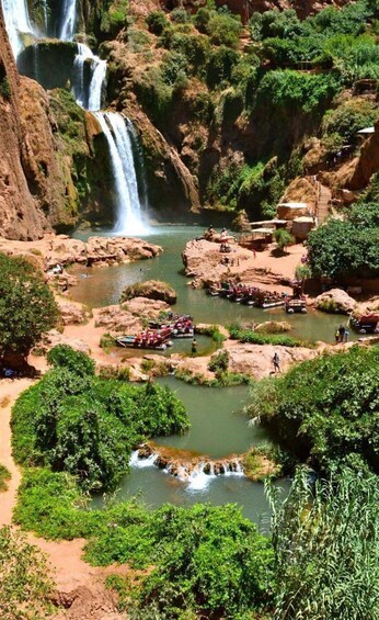 A waterfall cascading into a river surrounded by rocky terrain and lush greenery. 2
