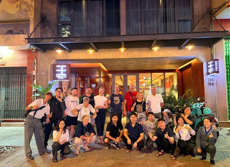 A group of people posing in front of a building with a sign that reads 'Hotel.' 3