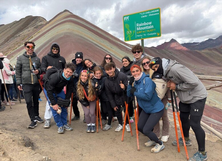 A group of people at Rainbow Mountain, with a sign indicating the distance to C.P. Chillihuani. 5