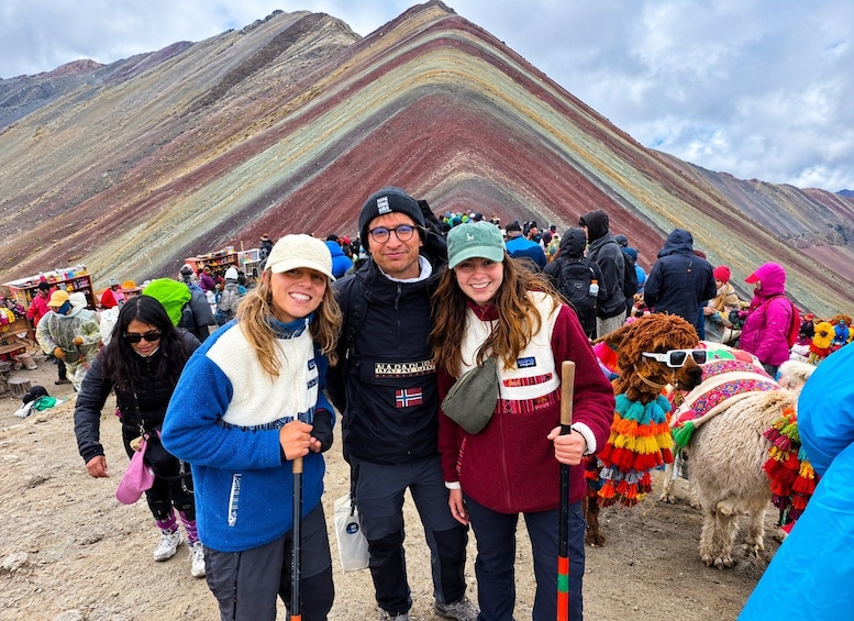 A group of people standing in front of a colorful mountain range. 1