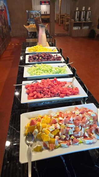 A buffet table with various fruits and a coffee machine in the background. 2