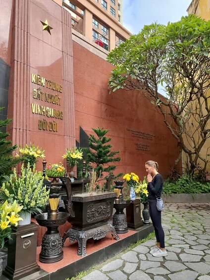 A person praying at a shrine with offerings of flowers and incense. 5