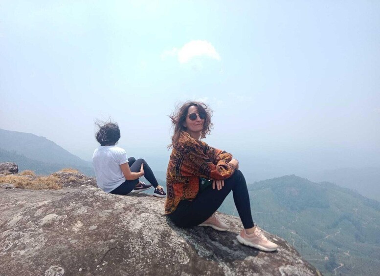 Two people sitting on a rock with a mountainous landscape in the background. 4