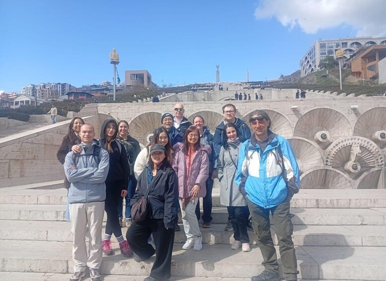 A group of people standing on steps with a large building and statues in the background. 2