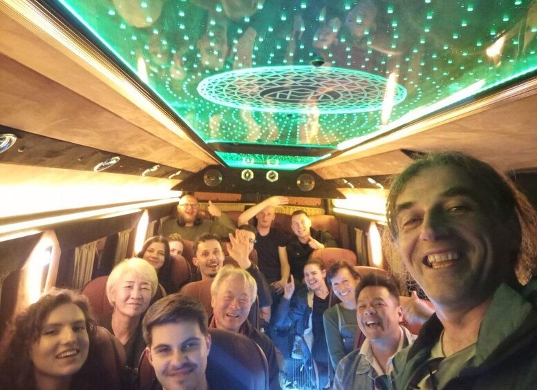 A group of people inside a train with a green-lit ceiling and circular patterns. 4