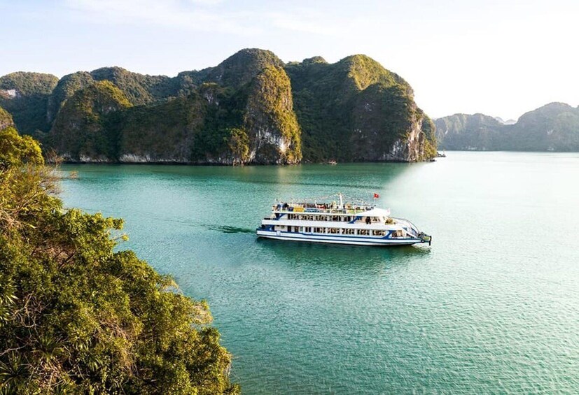 A boat on a calm body of water surrounded by lush green hills. 1