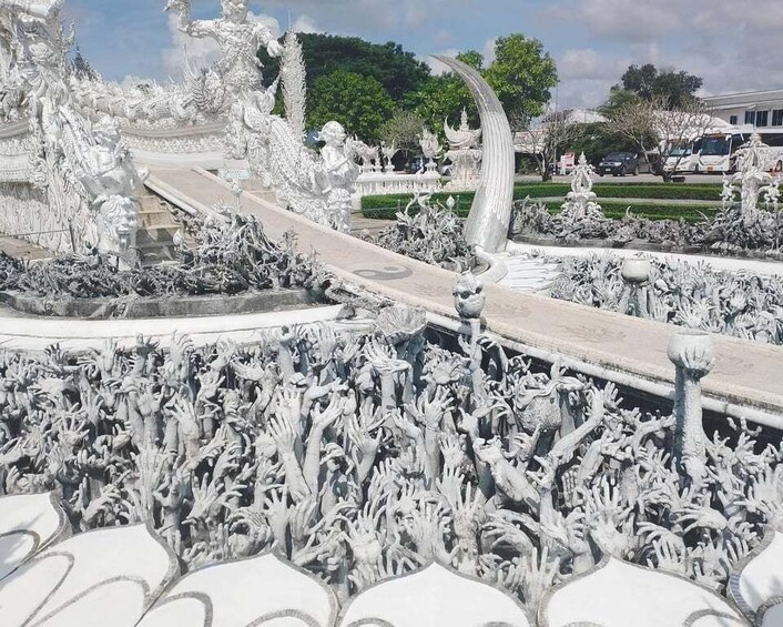 A white ornate temple with intricate carvings and statues, surrounded by a garden with a pathway leading to it. 2