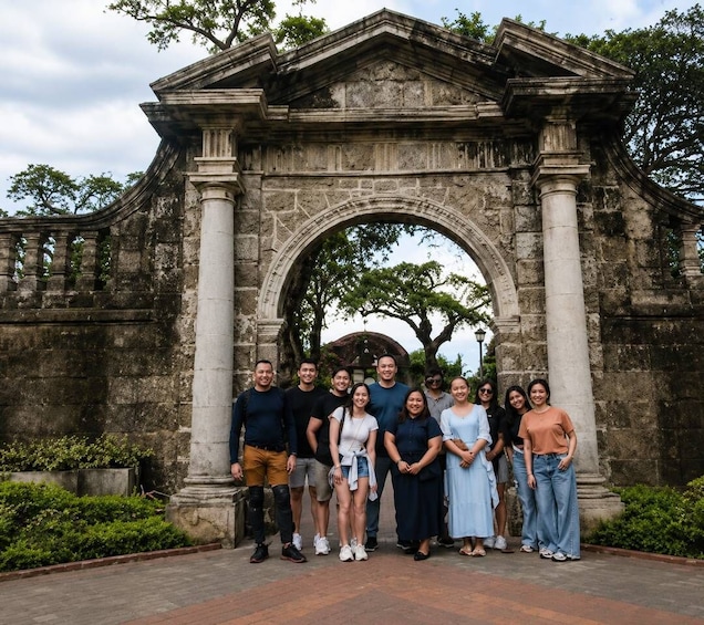 A group of people standing in front of a historic stone archway with columns. 4