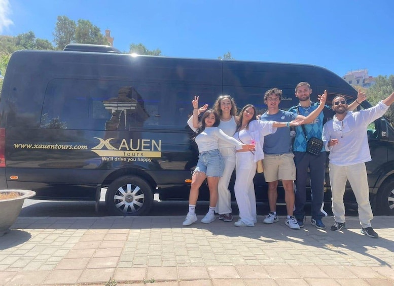 A group of people posing in front of a black van with 'XAUEN Tours' and 'We'll drive you happy' written on it. 5