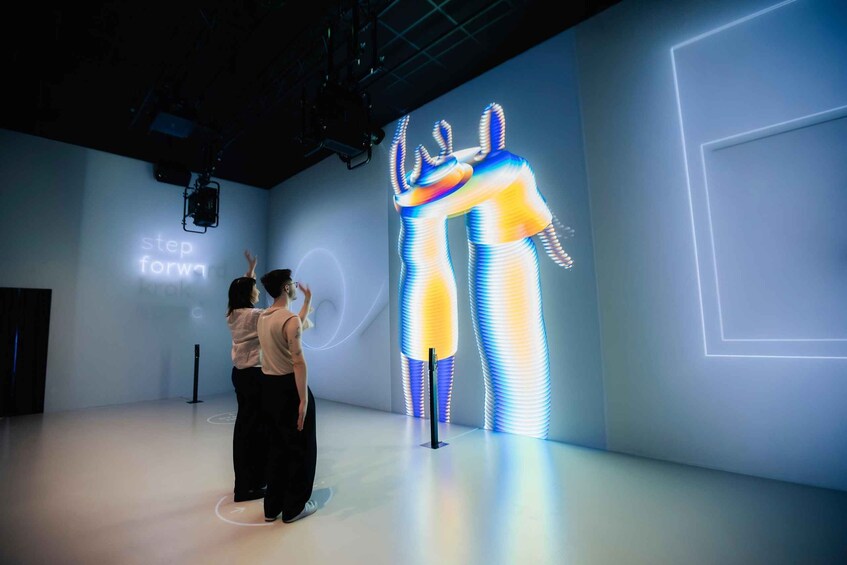 Une personne prend une photo d’une installation artistique numérique mettant en scène une figure humaine illuminée. 3