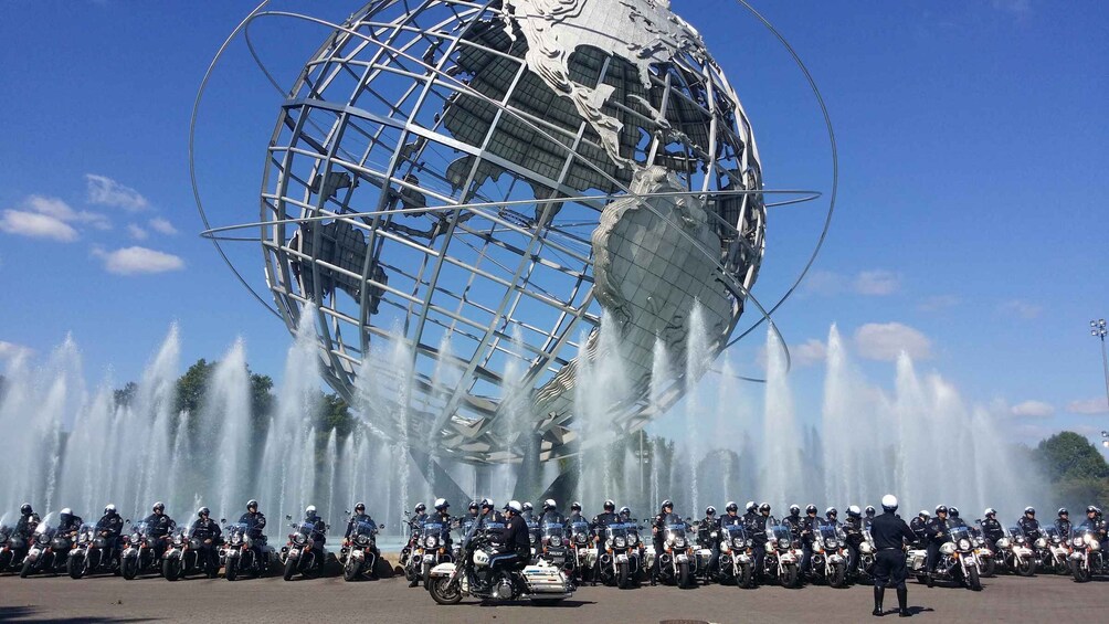A police motorcade in front of a large globe sculpture with water fountains. 3