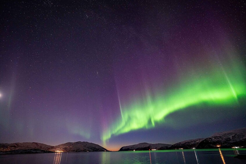 The Northern Lights over a calm lake with snow-covered hills. 4