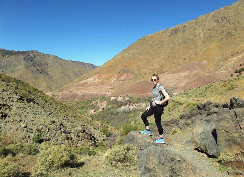 A person standing on a rocky outcrop with a mountainous landscape in the background. 4