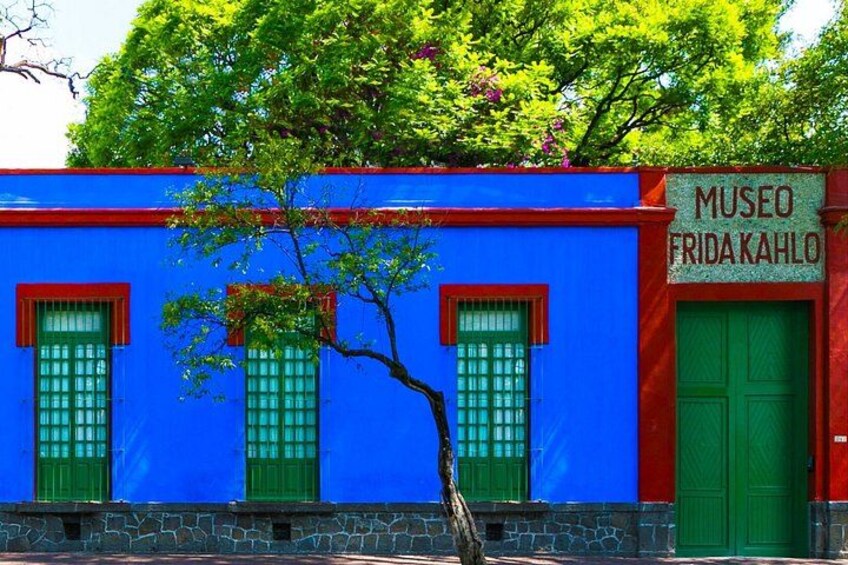 Ein Gebäude mit blauer Fassade, grünen Türen und Fenstern, mit dem Schild 'Museo Fridakahlo'. 2