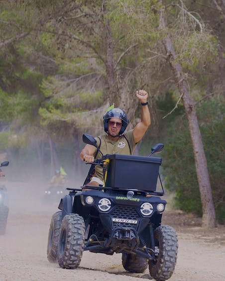 A person riding a black off-road vehicle on a dirt path surrounded by trees. 1
