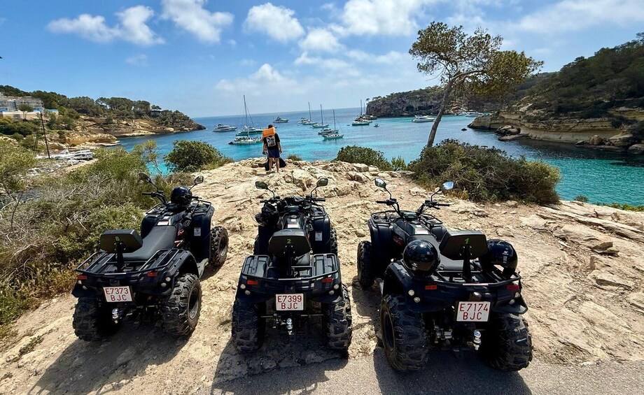 Four ATVs parked on a rocky path with a coastal view. 1