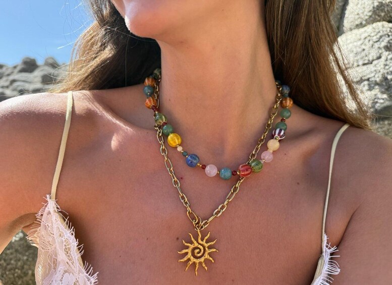 A person wearing a necklace with colorful beads and a sun pendant. 2