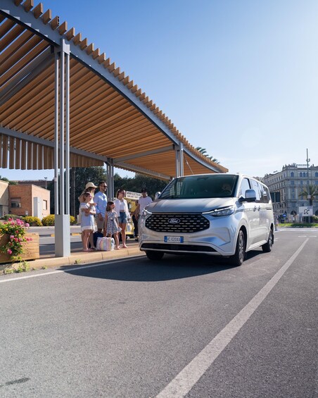 A white Ford SUV parked at a covered outdoor area with people standing nearby. 1
