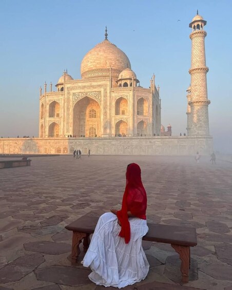 A person sitting on a bench facing the Taj Mahal. 1