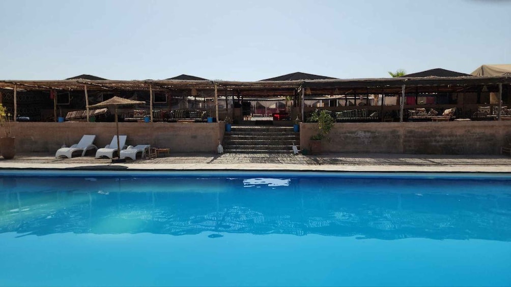 A swimming pool with lounge chairs and a covered seating area. 4