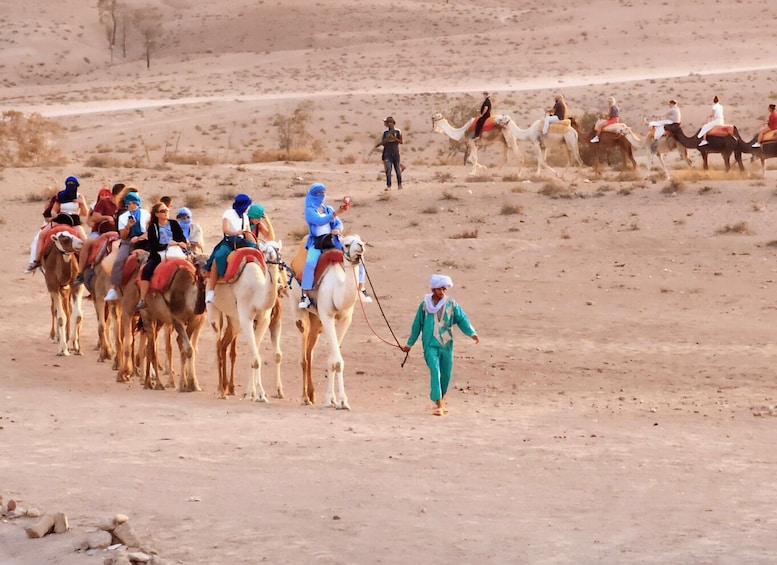 A group of people riding camels in a desert landscape. 2