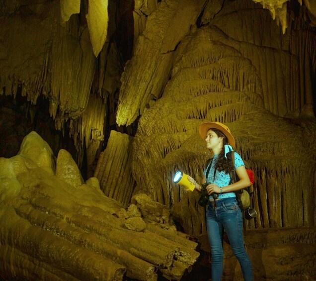 A person exploring a cave with stalactites and stalagmites. 1
