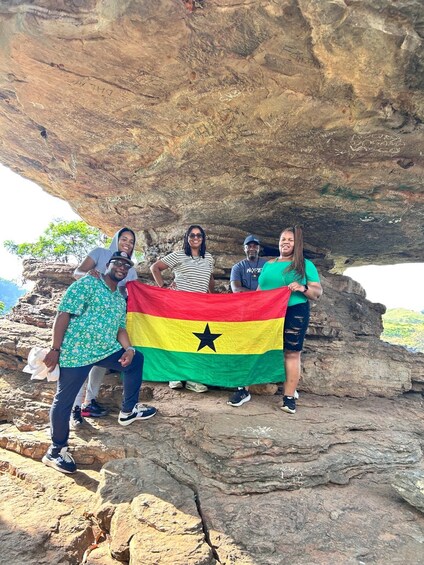 A group of people standing on a rocky outcrop with a flag. 5