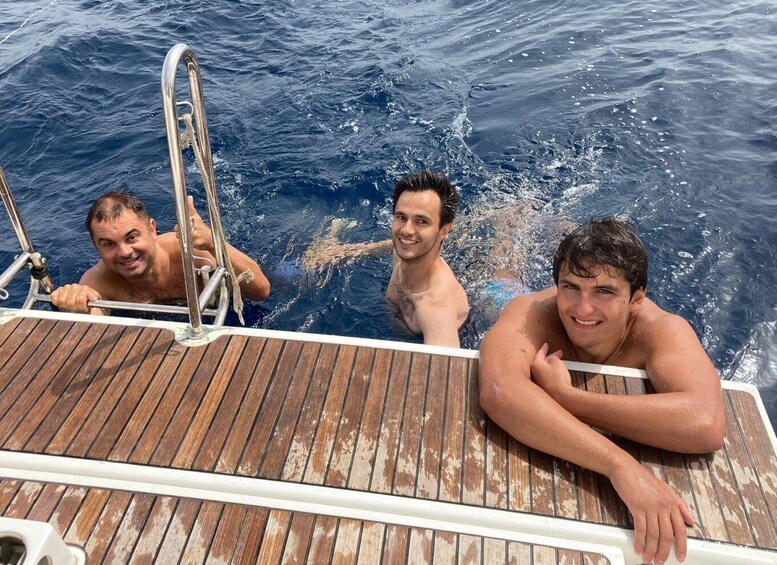 Three men on a boat deck with wooden planks and metal railings. 3