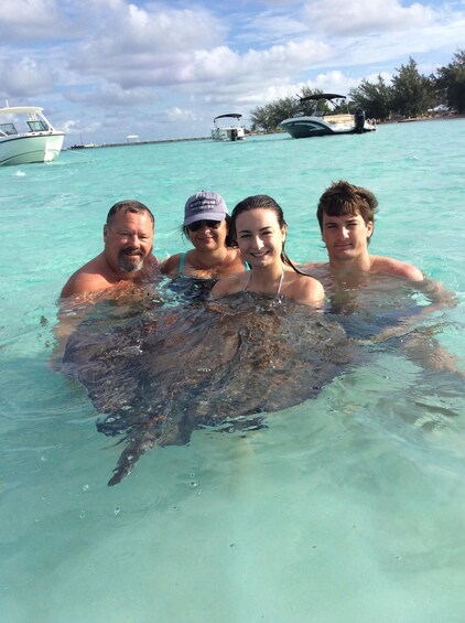 A family in clear turquoise water with a stingray. 3