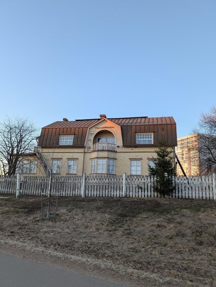 A two-story house with a brown roof and a white picket fence in front. 5
