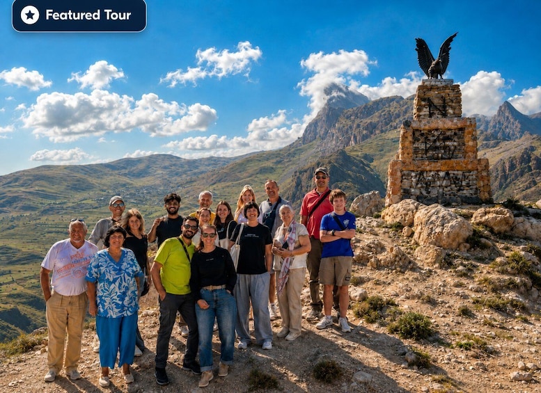 A group of people standing on a mountain with a statue of an eagle on a pedestal. 2
