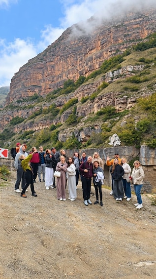 A group of people standing on a rocky path with a mountainous landscape in the background. 2