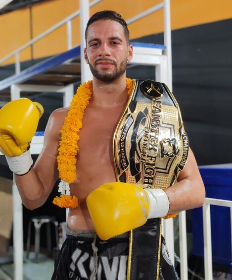 A boxer holding a championship belt with yellow gloves and a garland. 3