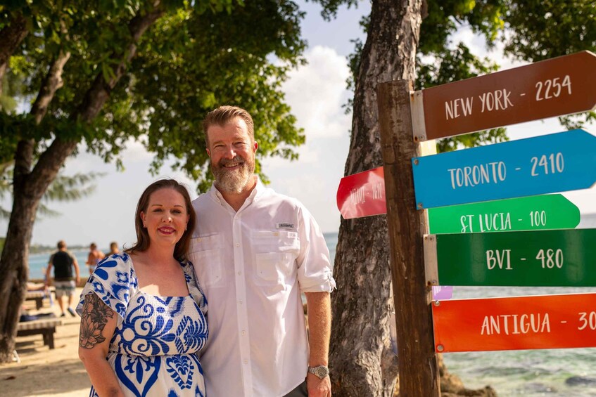 A couple standing by a signpost with city names and distances. 4
