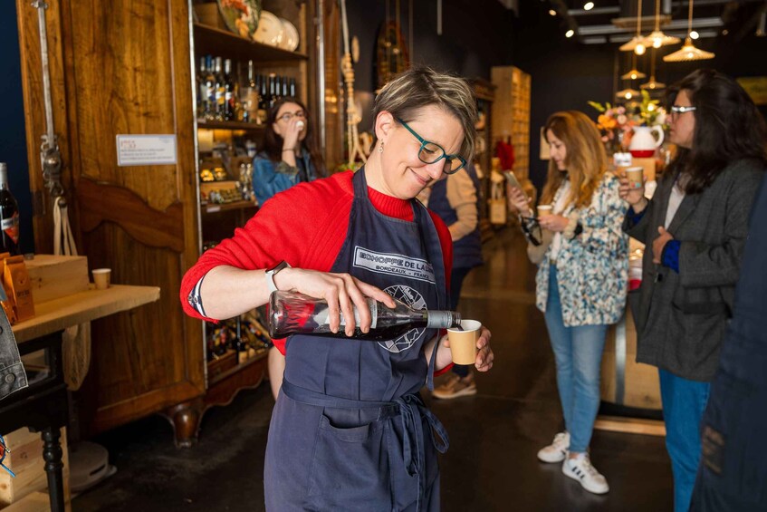 A person pouring a drink into a cup in a bar setting with shelves of bottles and other patrons. 3