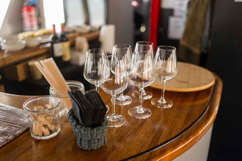 A bar setting with empty wine glasses, a napkin holder, and a glass jar with wooden utensils. 4