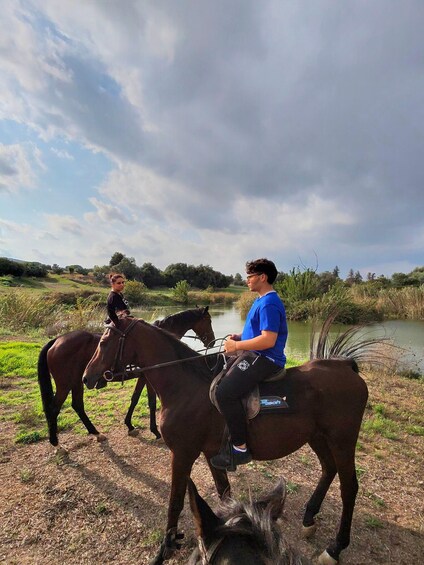 Dos personas montando caballos a orillas de un río. 4