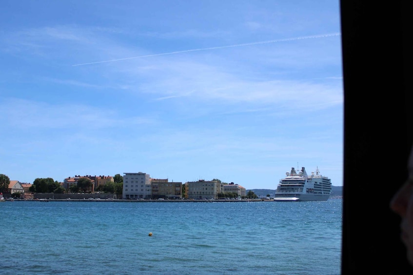 A cruise ship on a calm sea with buildings along the shore. 5