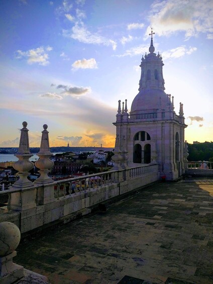A historic building with a dome and spire, overlooking a cityscape with a bridge and water. 3