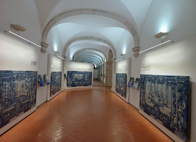 A corridor with tiled walls and arches, displaying blue and white artwork. 2