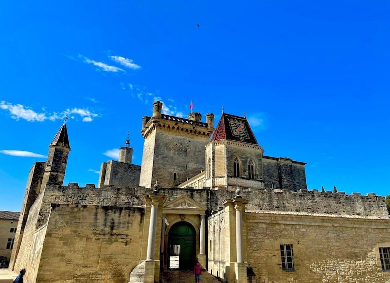 A historic castle with a prominent entrance, towers, and a clear blue sky. 2