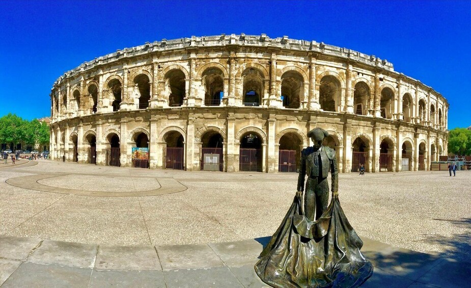 A historic amphitheater with a statue in the foreground. 1
