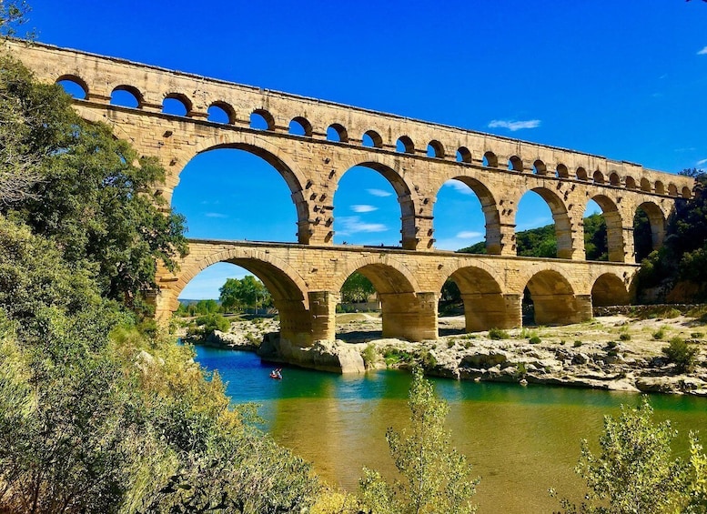 A stone aqueduct with multiple arches spanning a river. 4