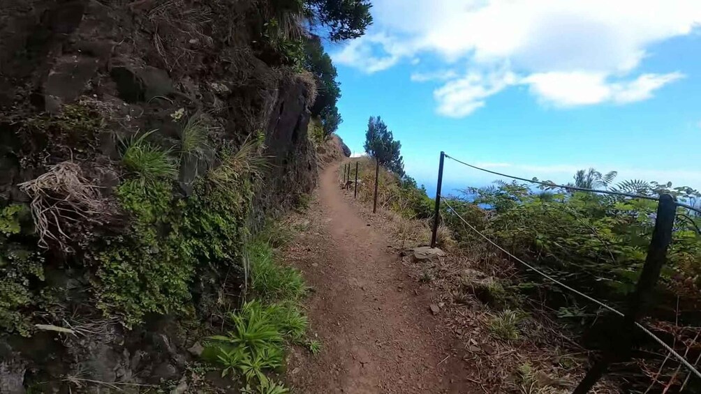 A dirt path flanked by rocky cliffs and vegetation, leading uphill. 2