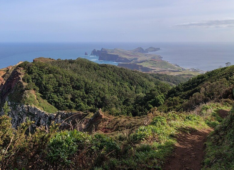 A coastal landscape with a dirt path leading to a cliff edge overlooking the sea. 4