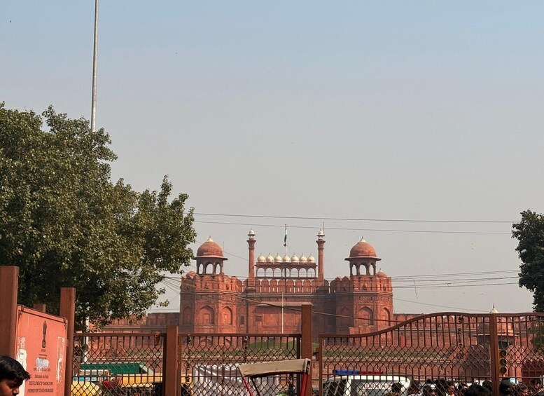 A large red building with domes and minarets, surrounded by a fence. 2