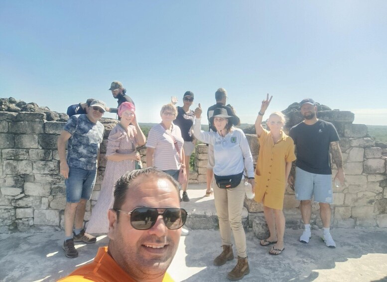 A group of people standing on a stone wall with a clear sky in the background. 4