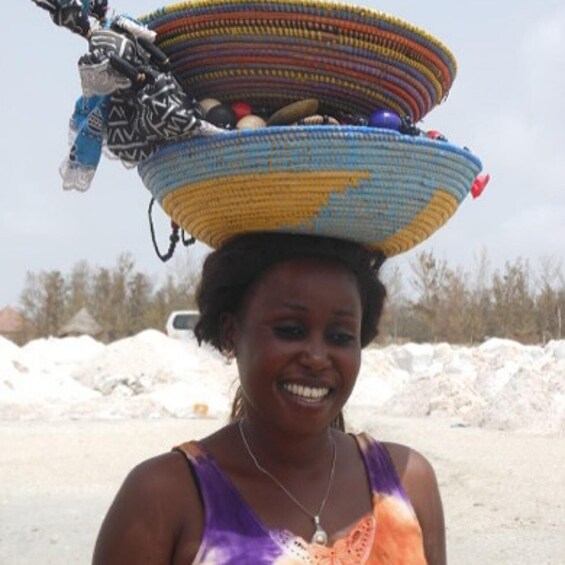 A person carrying a colorful woven basket on their head. 4