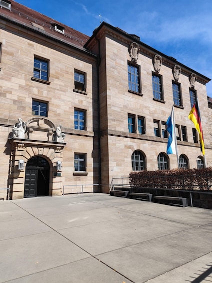 A historic building with a stone facade, arched entrance, and classical sculptures. 5
